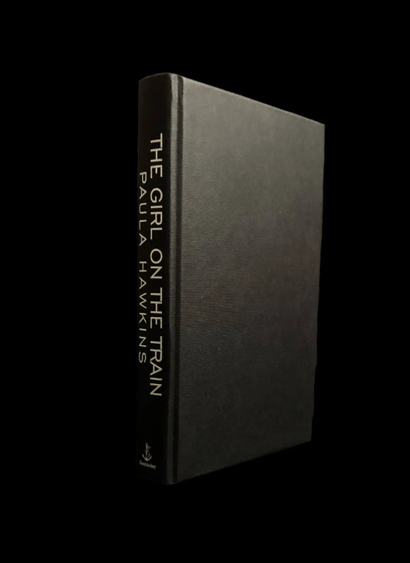 A hardcover book titled 'The Girl on the Train' by Paula Hawkins.