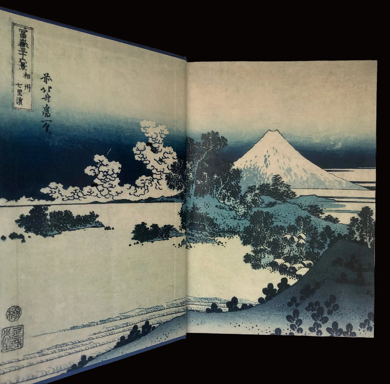 Woodblock print of Mount Fuji with trees and water, open book format.