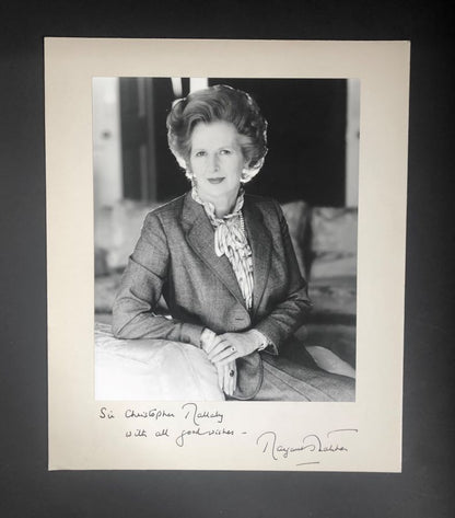 A black and white portrait photograph of Margaret Thatcher with a handwritten inscription and signature.