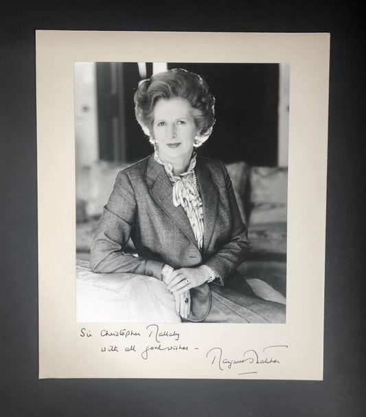 A black and white portrait photograph of Margaret Thatcher with a handwritten inscription and signature.